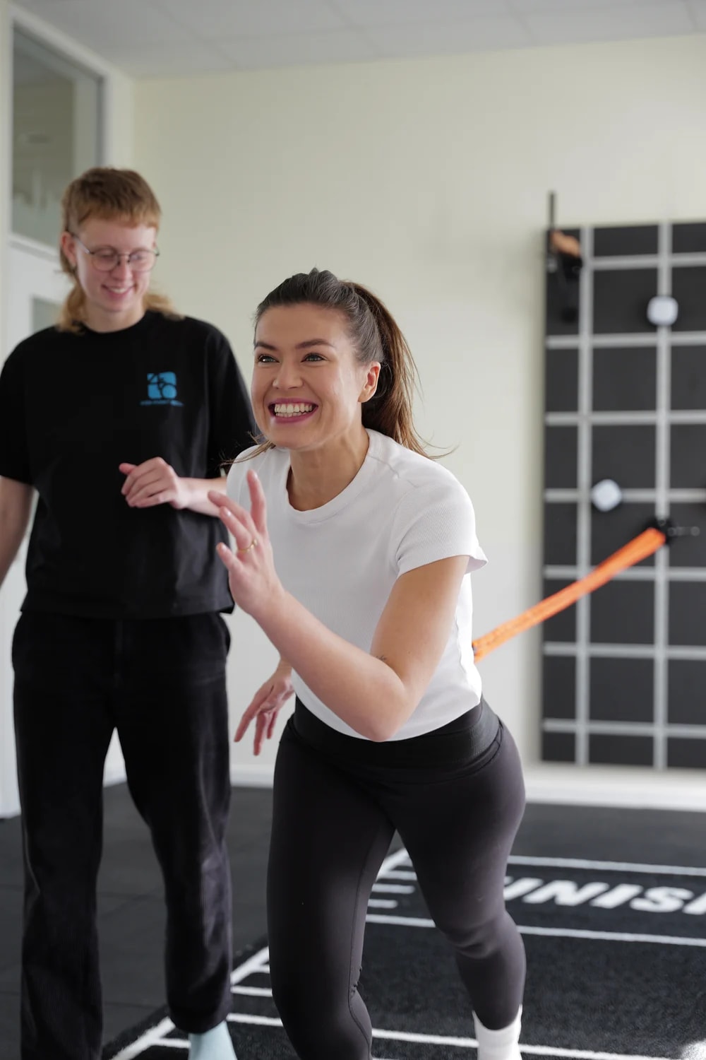 Zwei Therapeut:innen leiten eine Übung mit dem Widerstandsband im Trainingsraum an.