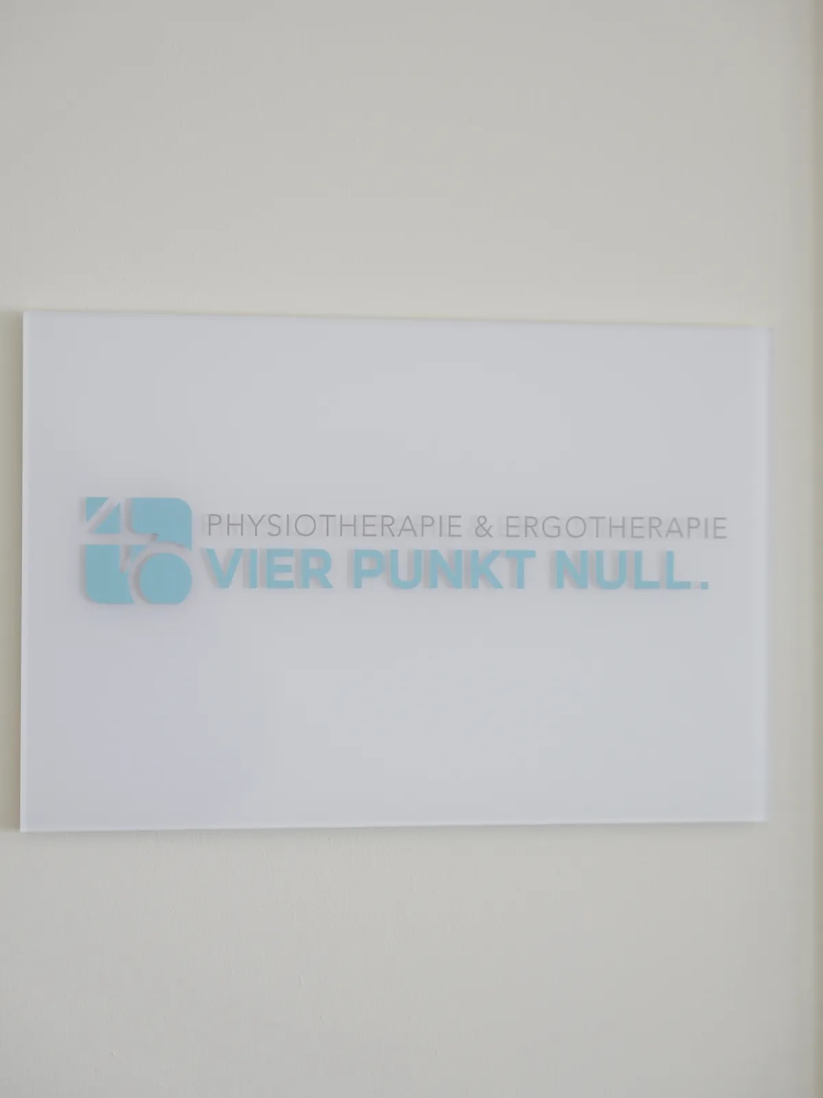 Wandschild mit dem Logo und dem Schriftzug Physiotherapie & Ergotherapie VIER PUNKT NULL.