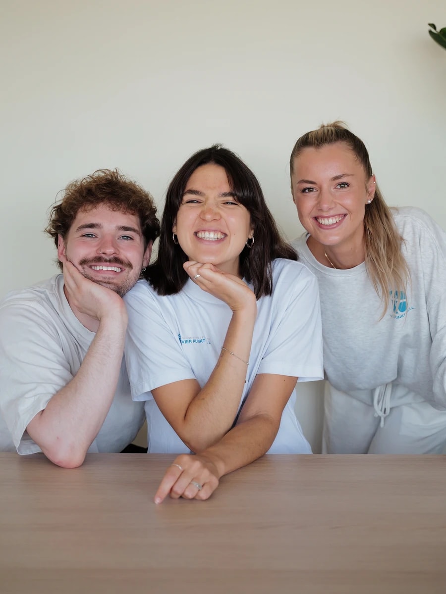 Drei Mitglieder des Teams von Vier Punkt Null nebeneinander, in Praxis-Shirts, lachend.